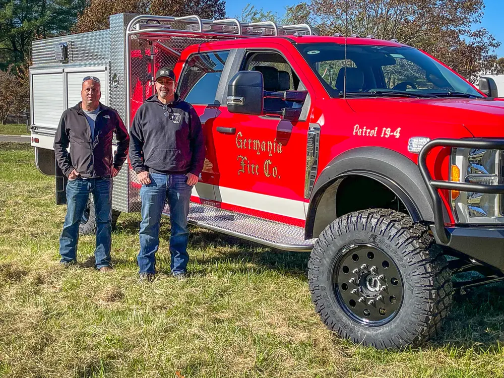 Close-up of two people beside driver-side door and front wheel.