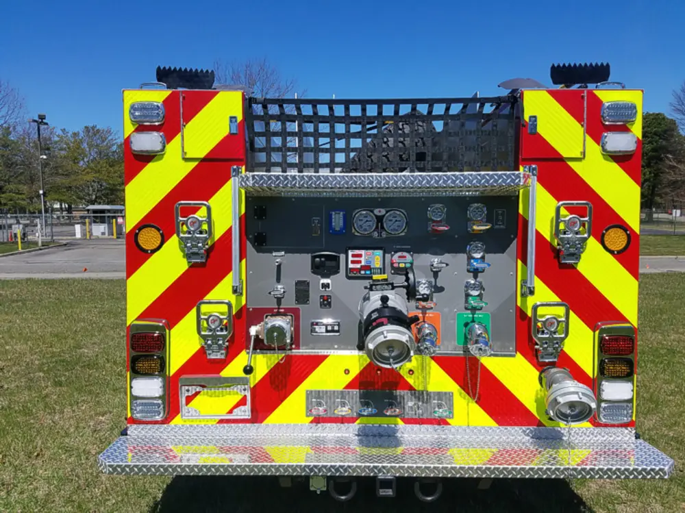 Exterior view of small fire truck showing cab, body compartments, and wheel/tire area.