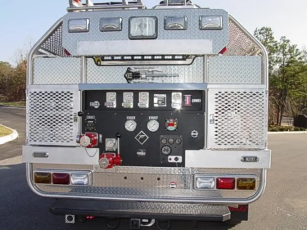 Exterior view of small fire truck showing cab, body compartments, and wheel/tire area.