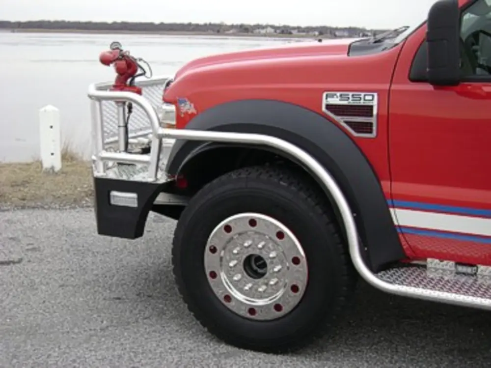 Exterior view of small fire truck showing cab, body compartments, and wheel/tire area.