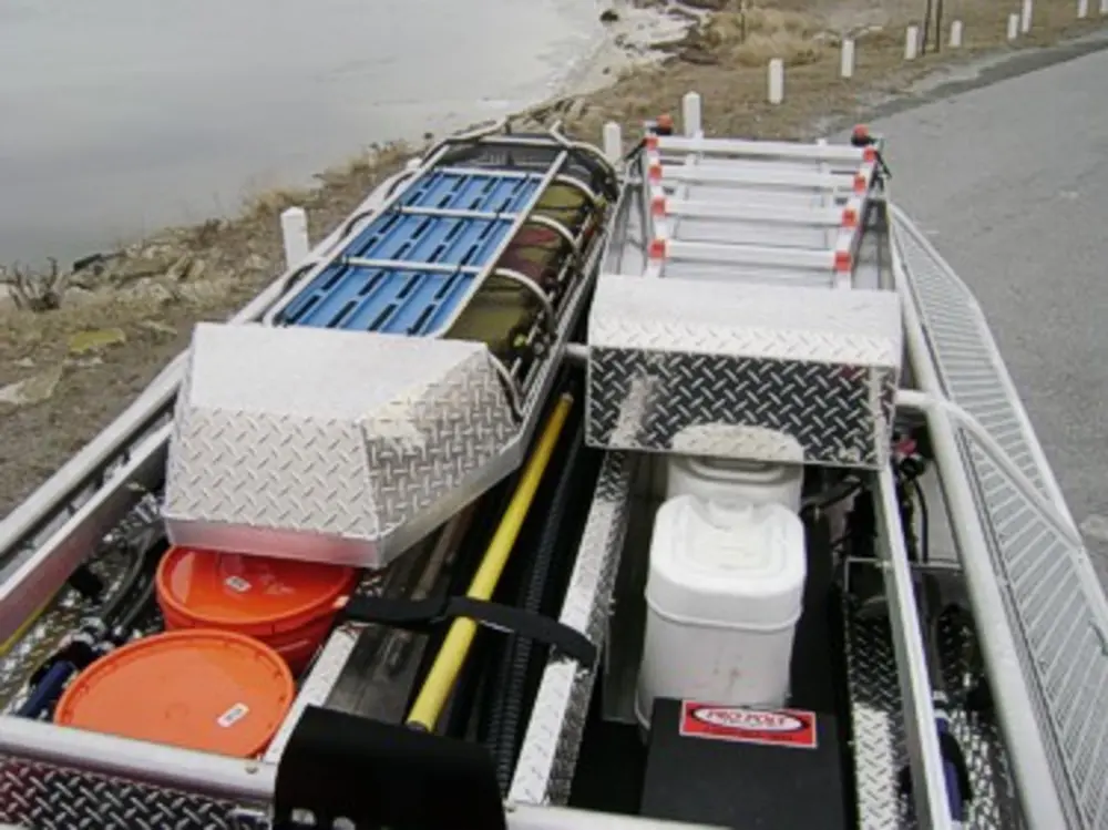 Exterior view of small fire truck showing cab, body compartments, and wheel/tire area.