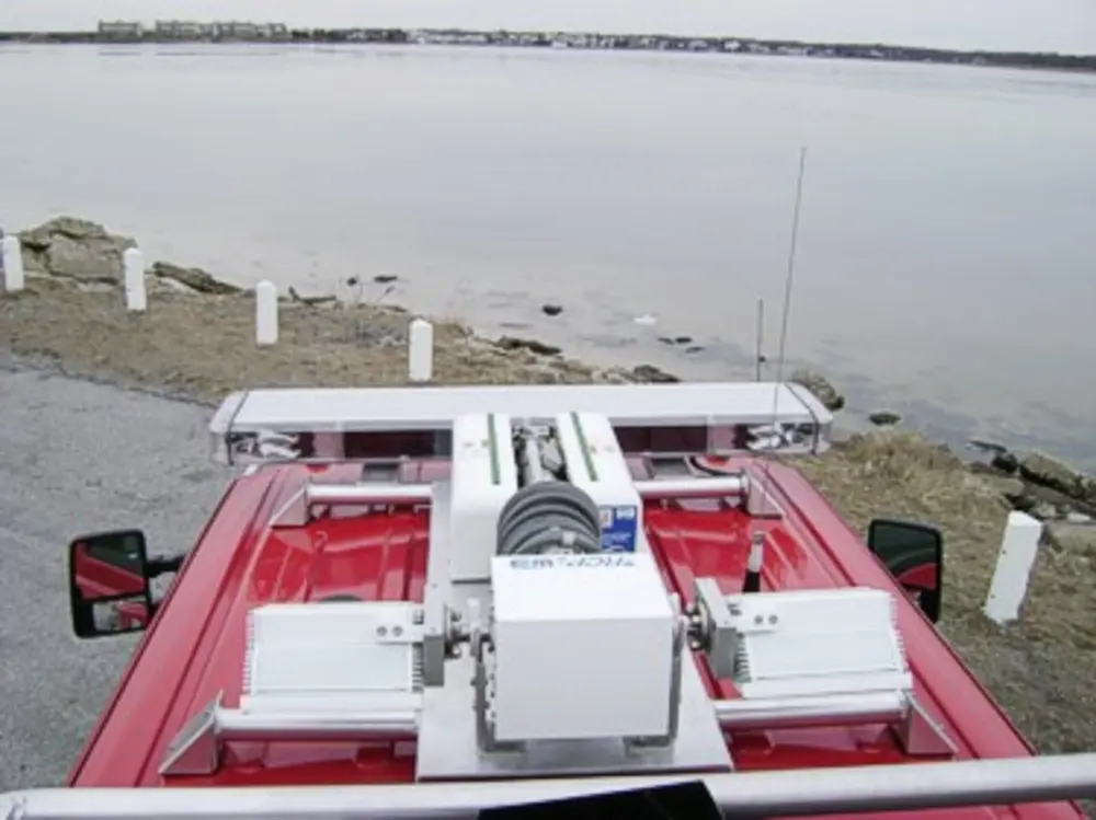 Exterior view of small fire truck showing cab, body compartments, and wheel/tire area.