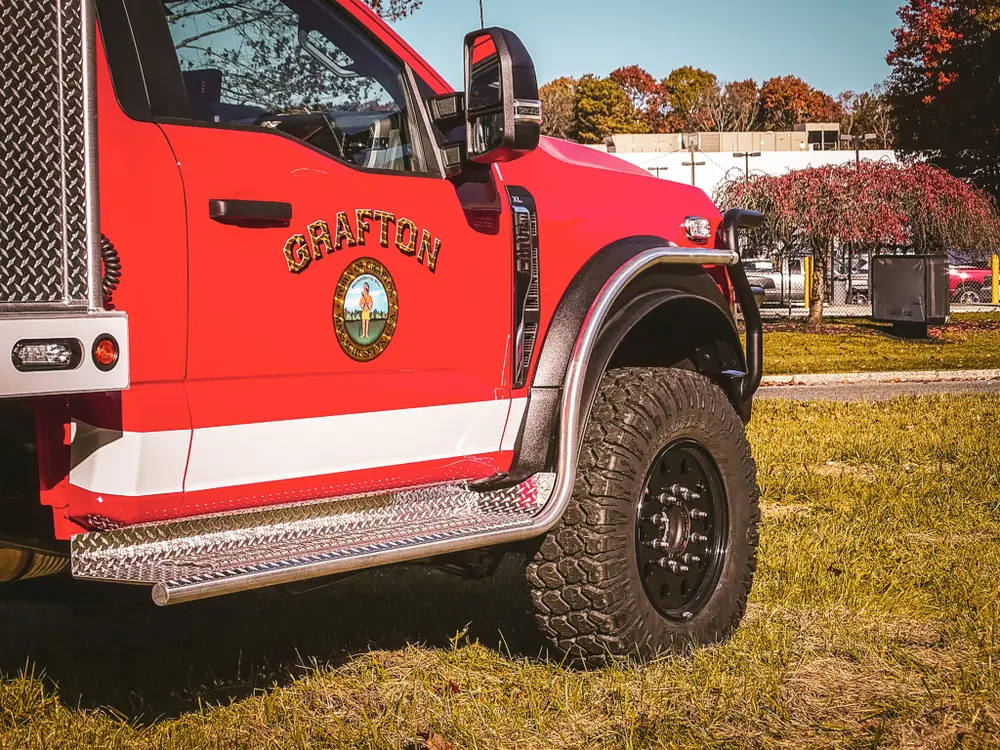 Driver door emblem and side-step close-up on red cab.