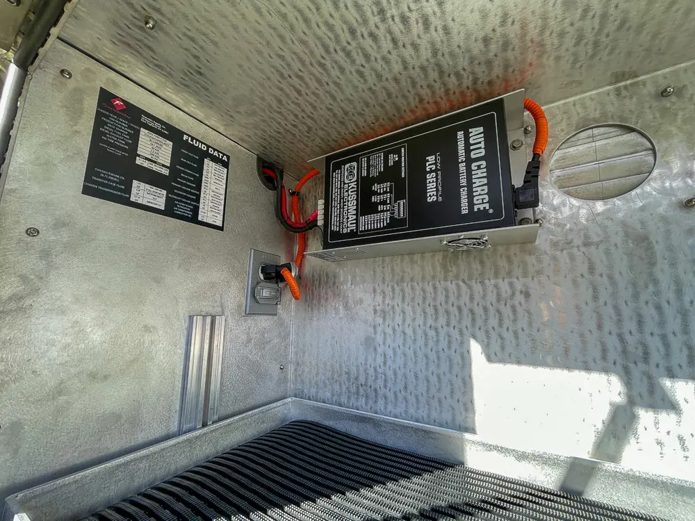 Side compartment interior with mounted charger and warning label.