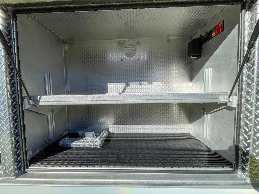 Open side compartment with two shelves and small items on floor.