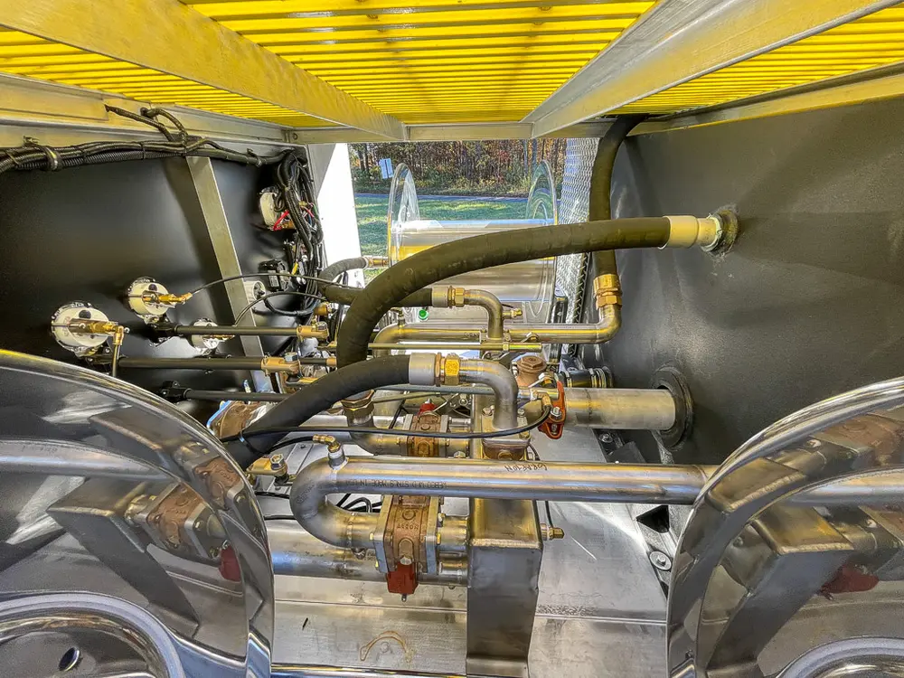 Pump compartment close-up with hoses, valves, and plumbing under top deck.