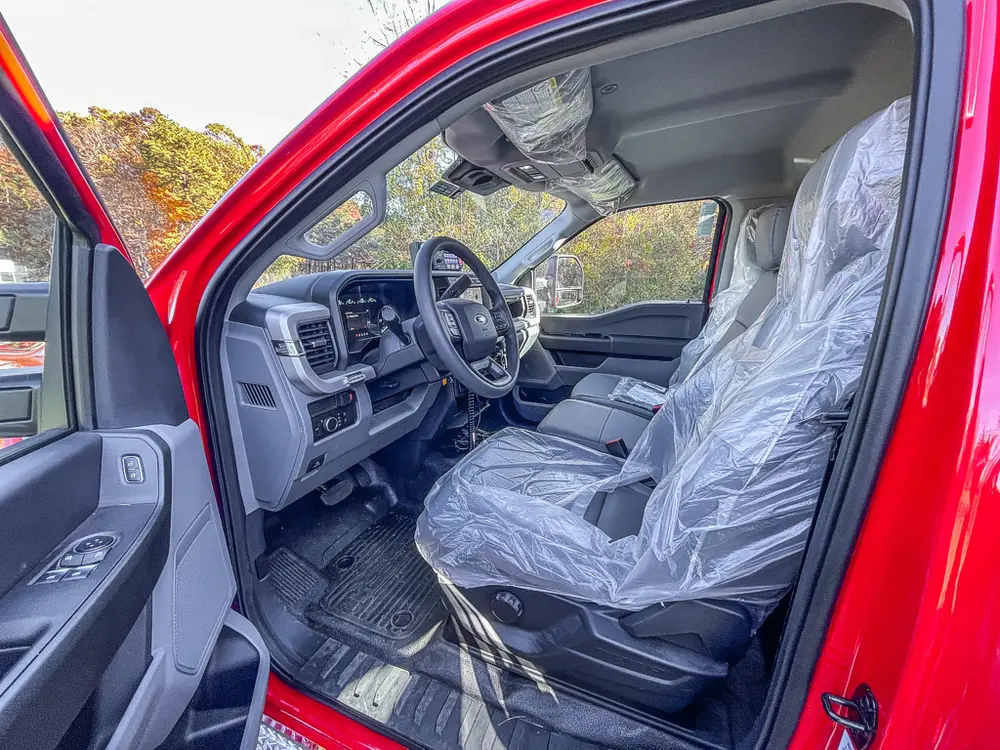Open driver door view showing front seats with protective covers.