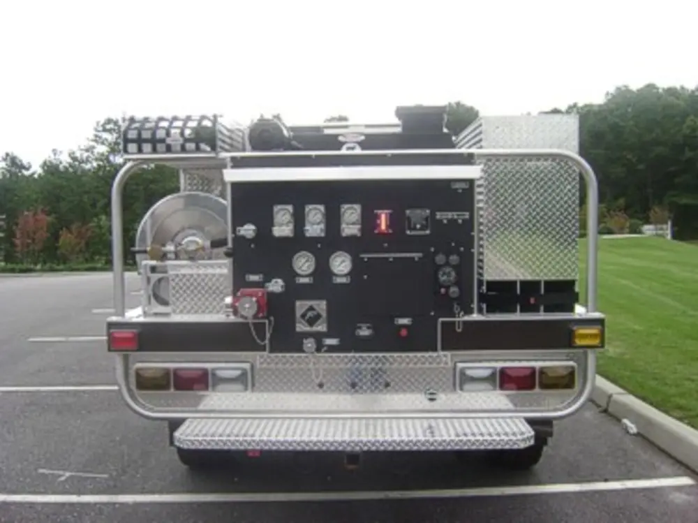 Exterior view of small fire truck showing cab, body compartments, and wheel/tire area.