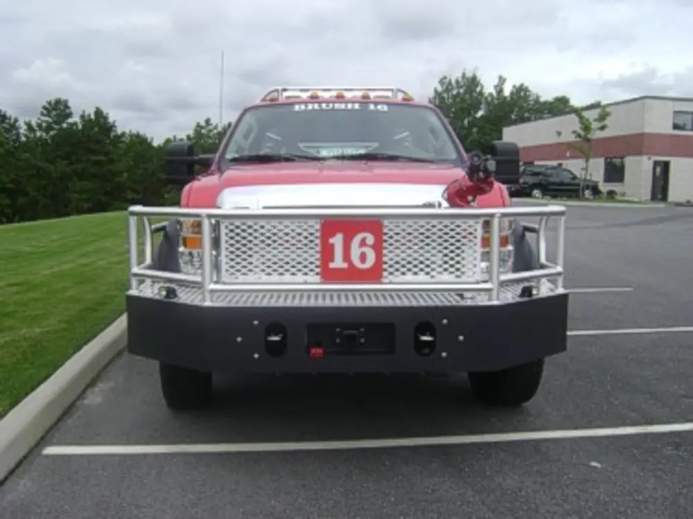 Exterior view of small fire truck showing cab, body compartments, and wheel/tire area.