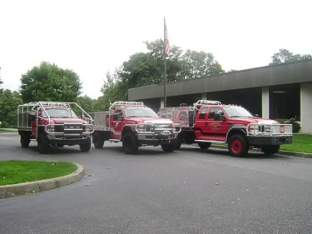 Exterior view of small fire truck showing cab, body compartments, and wheel/tire area.