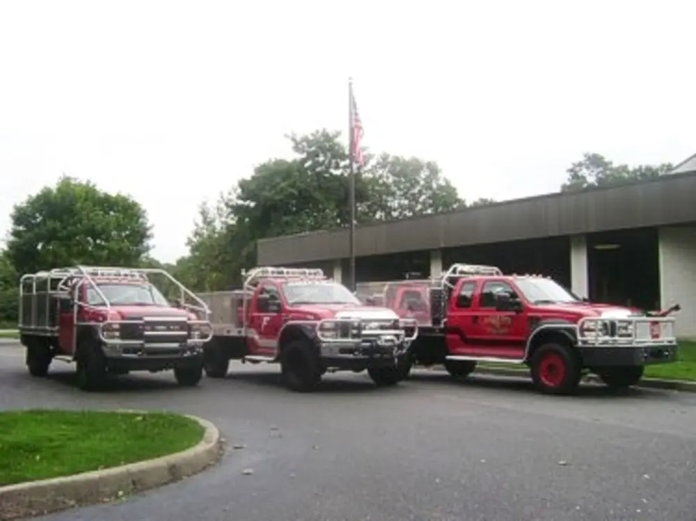 Exterior view of small fire truck showing cab, body compartments, and wheel/tire area.