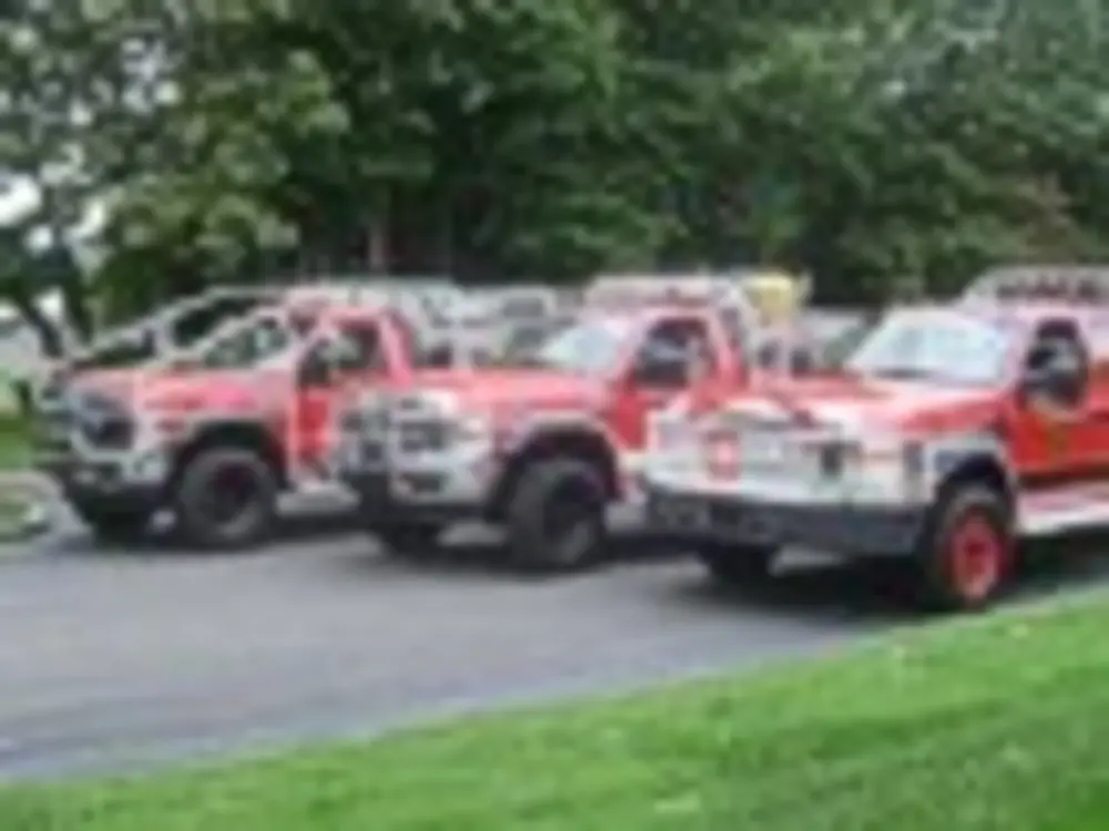 Exterior view of small fire truck showing cab, body compartments, and wheel/tire area.
