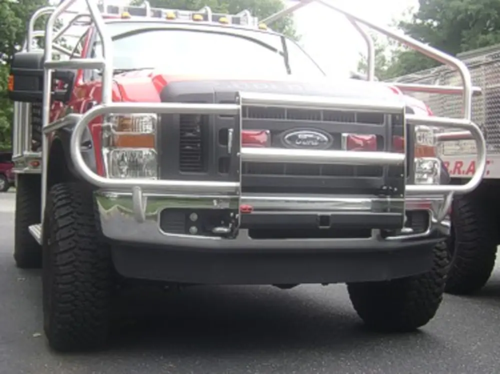Exterior view of small fire truck showing cab, body compartments, and wheel/tire area.