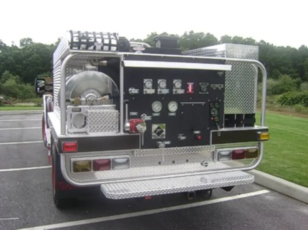 Exterior view of small fire truck showing cab, body compartments, and wheel/tire area.