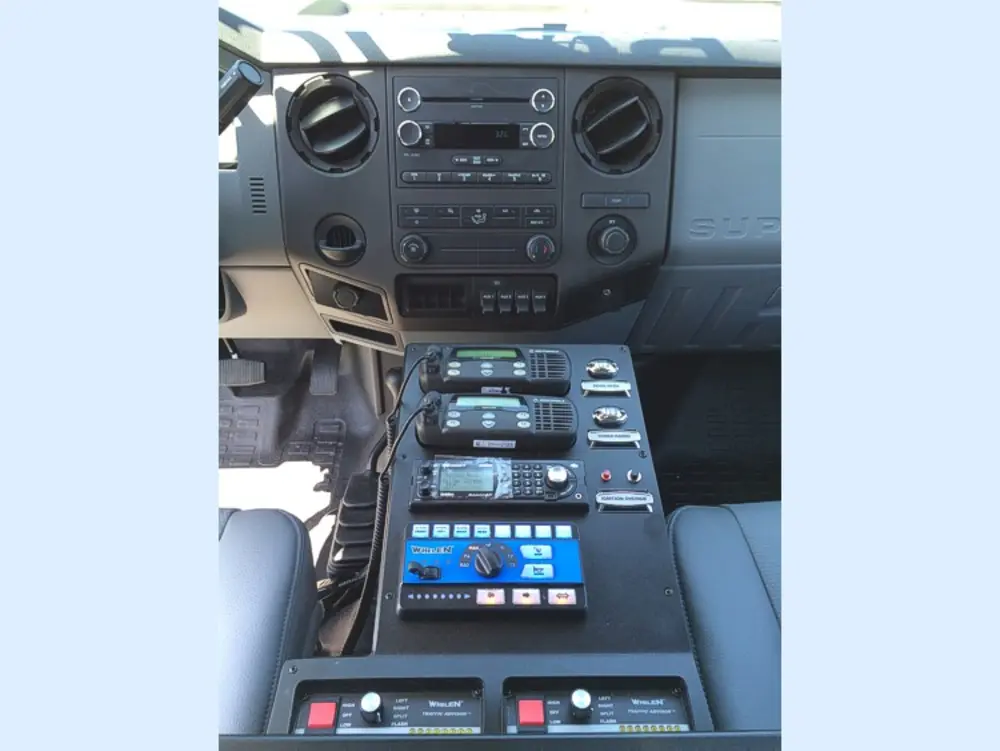Exterior view of small fire truck showing cab, body compartments, and wheel/tire area.
