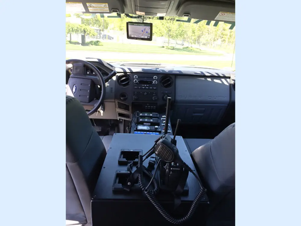 Exterior view of small fire truck showing cab, body compartments, and wheel/tire area.