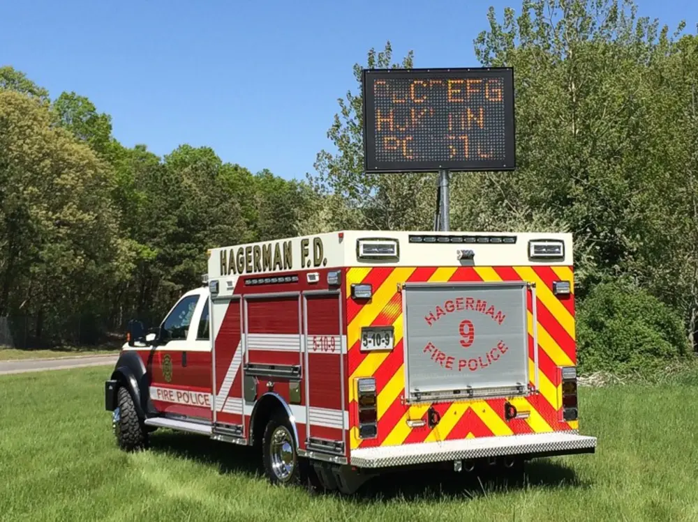 Exterior view of small fire truck showing cab, body compartments, and wheel/tire area.