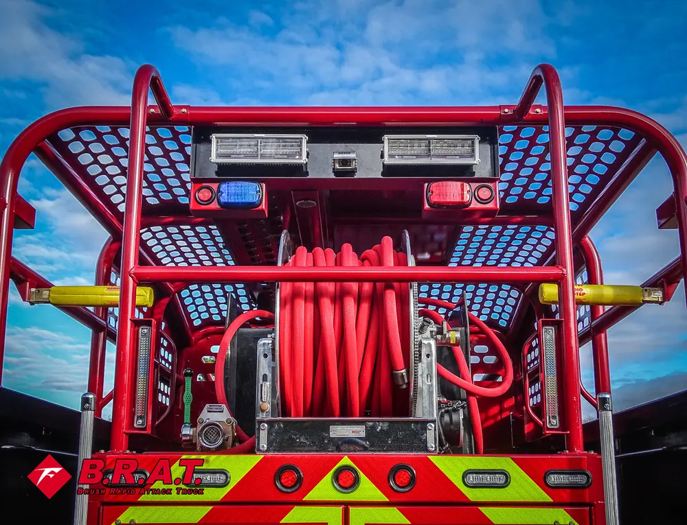 Exterior view of small fire truck showing cab, body compartments, and wheel/tire area.