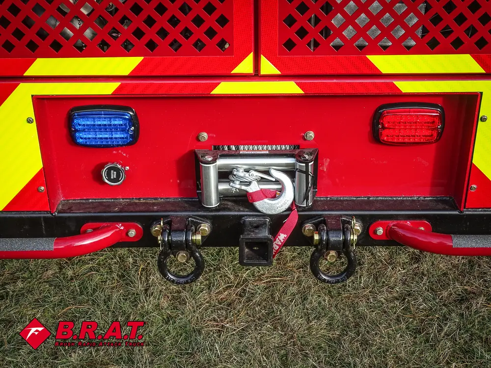 Exterior view of small fire truck showing cab, body compartments, and wheel/tire area.