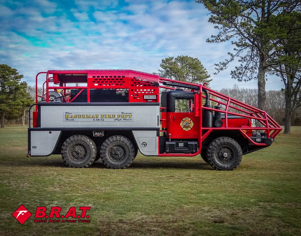 Exterior view of small fire truck showing cab, body compartments, and wheel/tire area.