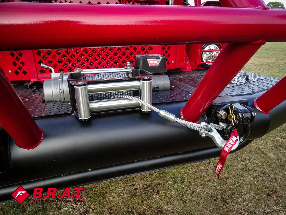 Exterior view of small fire truck showing cab, body compartments, and wheel/tire area.