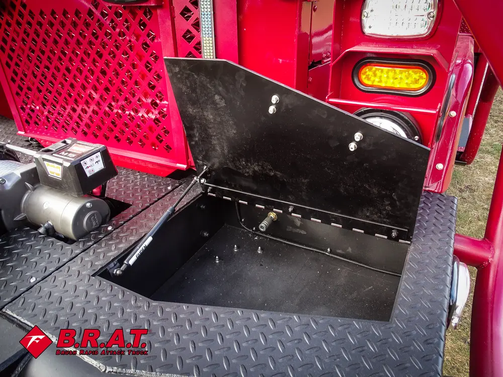 Exterior view of small fire truck showing cab, body compartments, and wheel/tire area.