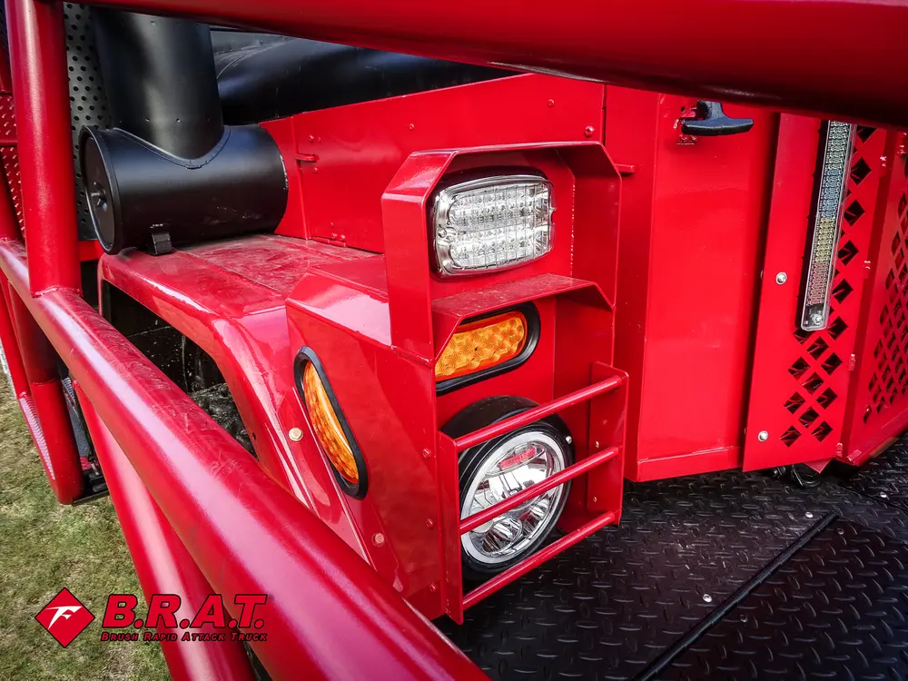 Exterior view of small fire truck showing cab, body compartments, and wheel/tire area.
