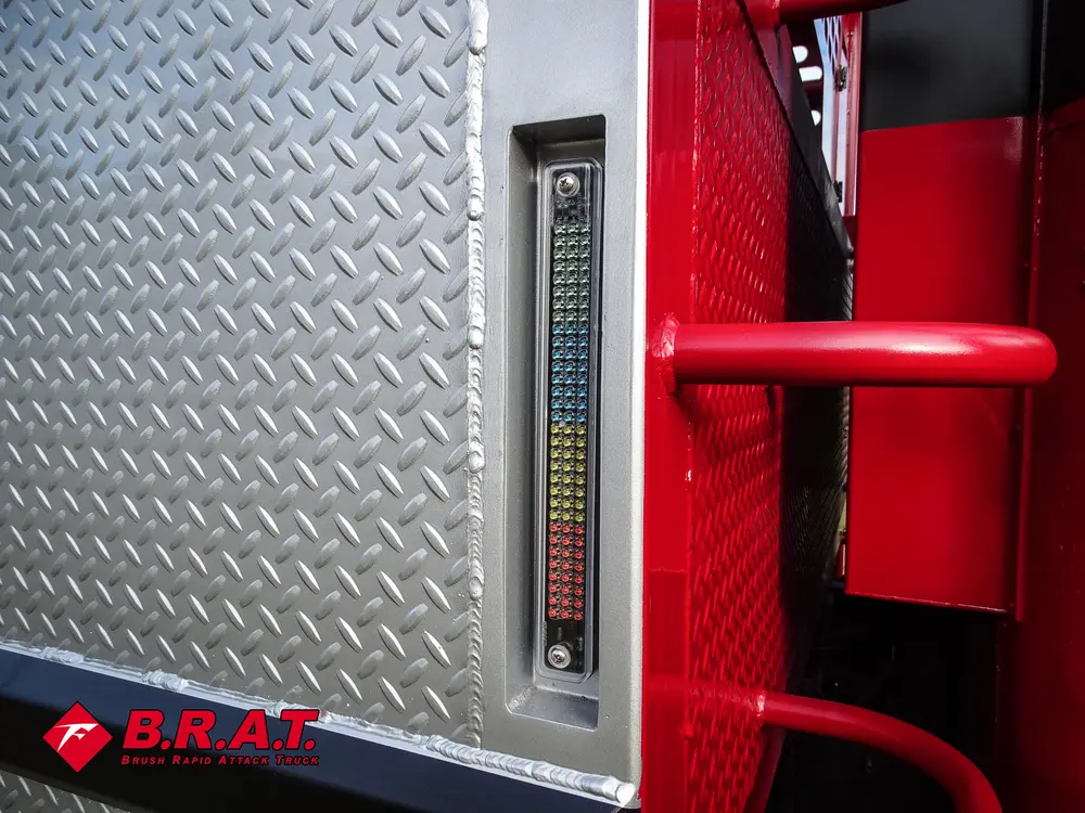 Exterior view of small fire truck showing cab, body compartments, and wheel/tire area.