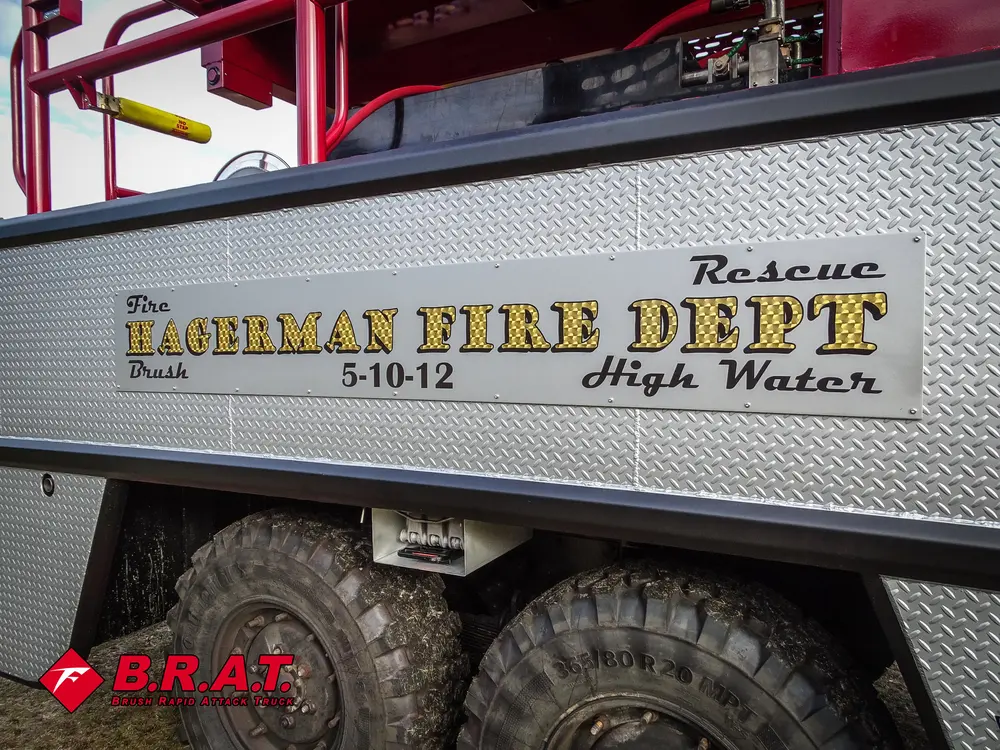Exterior view of small fire truck showing cab, body compartments, and wheel/tire area.
