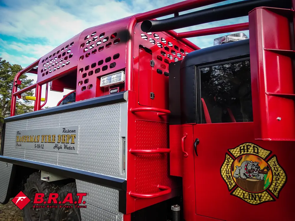 Exterior view of small fire truck showing cab, body compartments, and wheel/tire area.