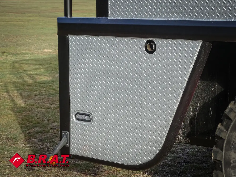 Exterior view of small fire truck showing cab, body compartments, and wheel/tire area.