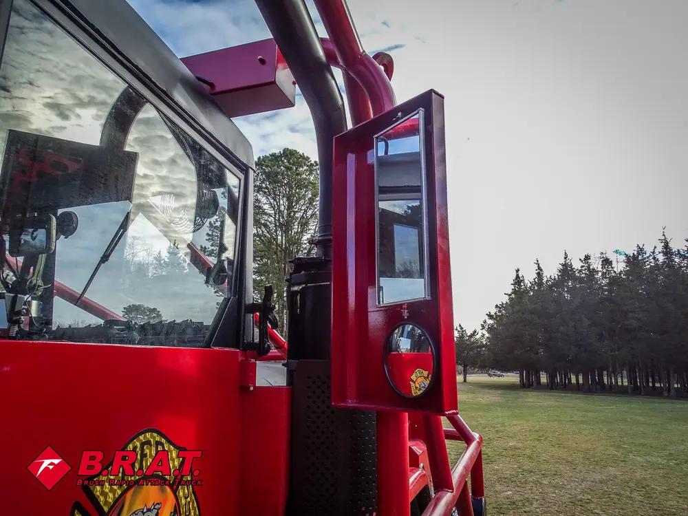 Exterior view of small fire truck showing cab, body compartments, and wheel/tire area.
