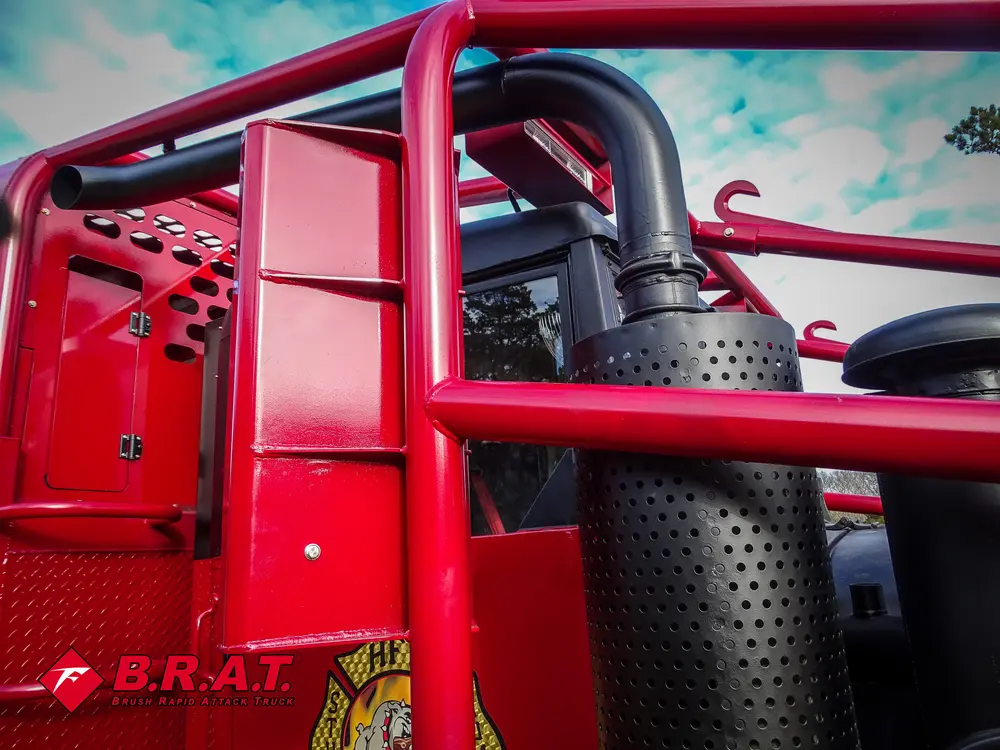 Exterior view of small fire truck showing cab, body compartments, and wheel/tire area.