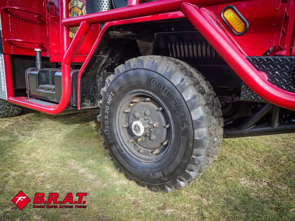 Exterior view of small fire truck showing cab, body compartments, and wheel/tire area.