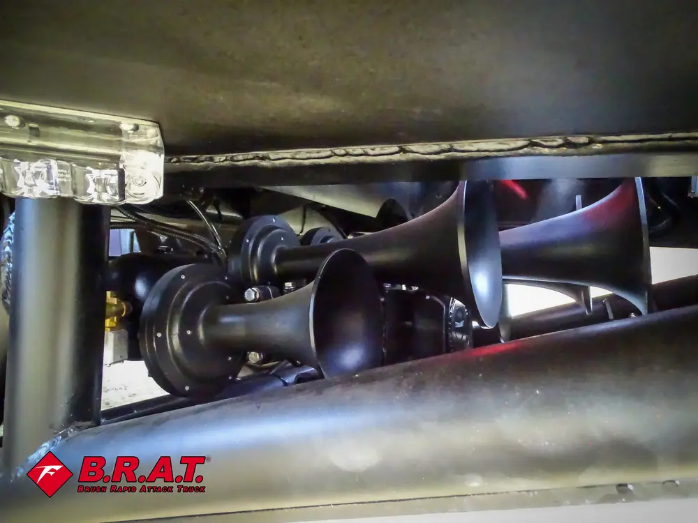 Exterior view of small fire truck showing cab, body compartments, and wheel/tire area.