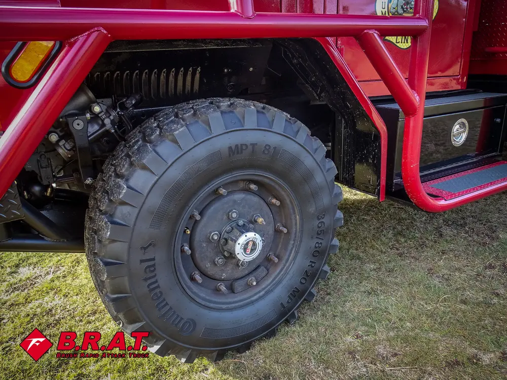 Exterior view of small fire truck showing cab, body compartments, and wheel/tire area.