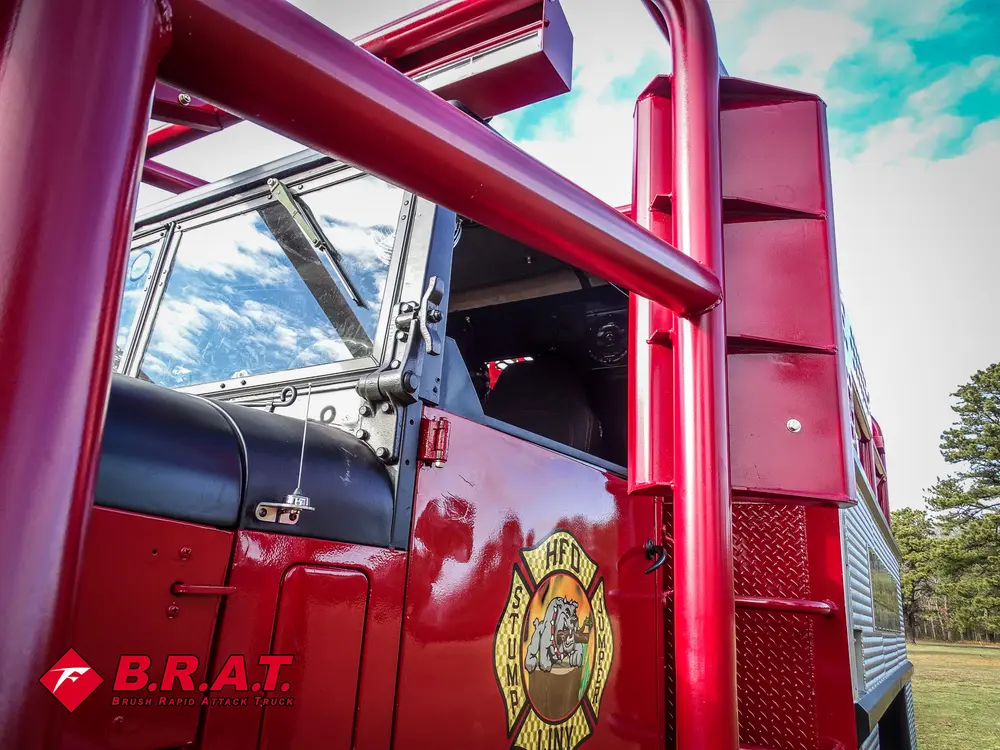 Exterior view of small fire truck showing cab, body compartments, and wheel/tire area.