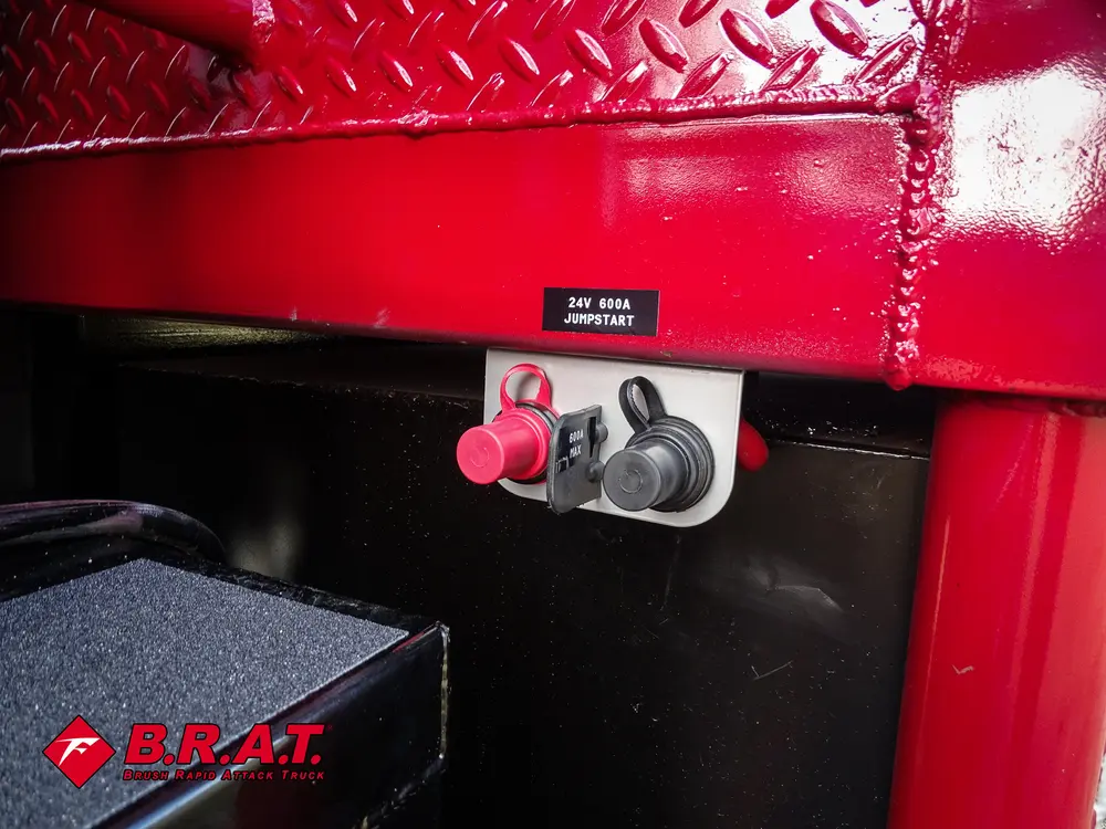 Exterior view of small fire truck showing cab, body compartments, and wheel/tire area.