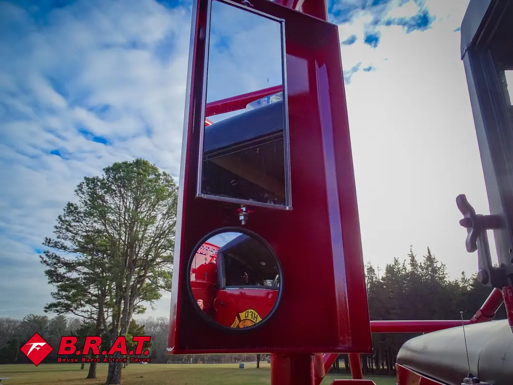 Exterior view of small fire truck showing cab, body compartments, and wheel/tire area.