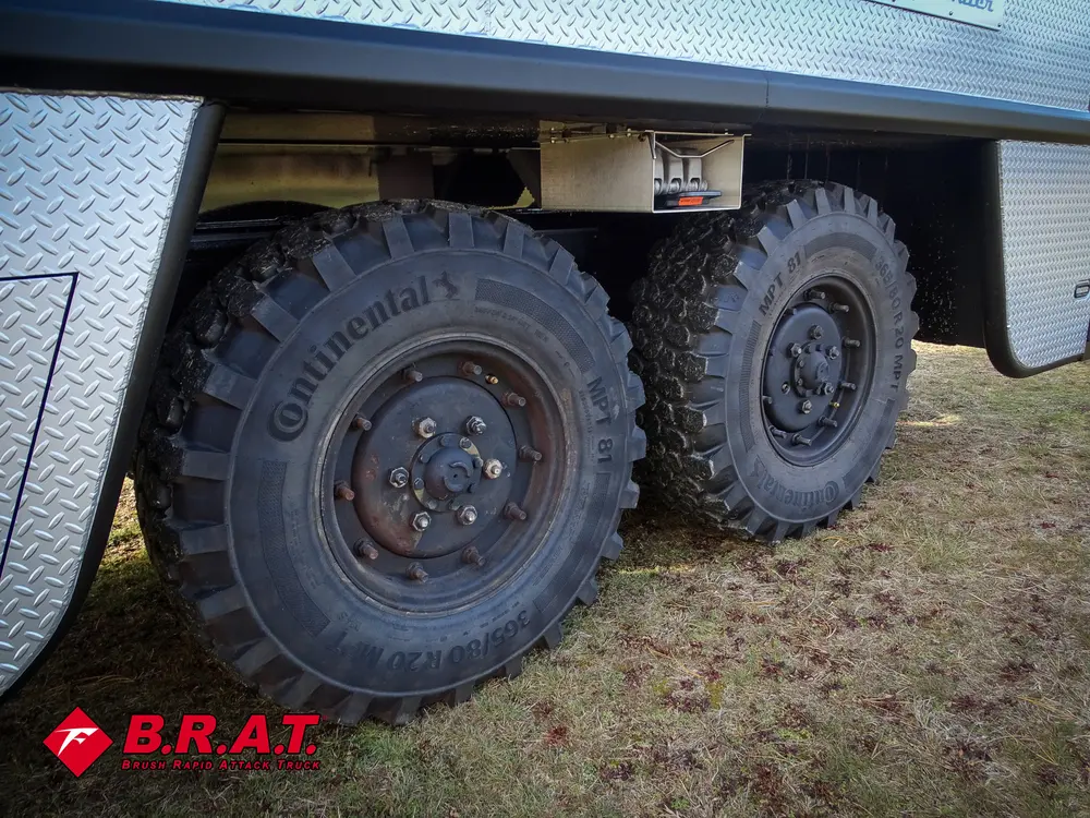 Exterior view of small fire truck showing cab, body compartments, and wheel/tire area.