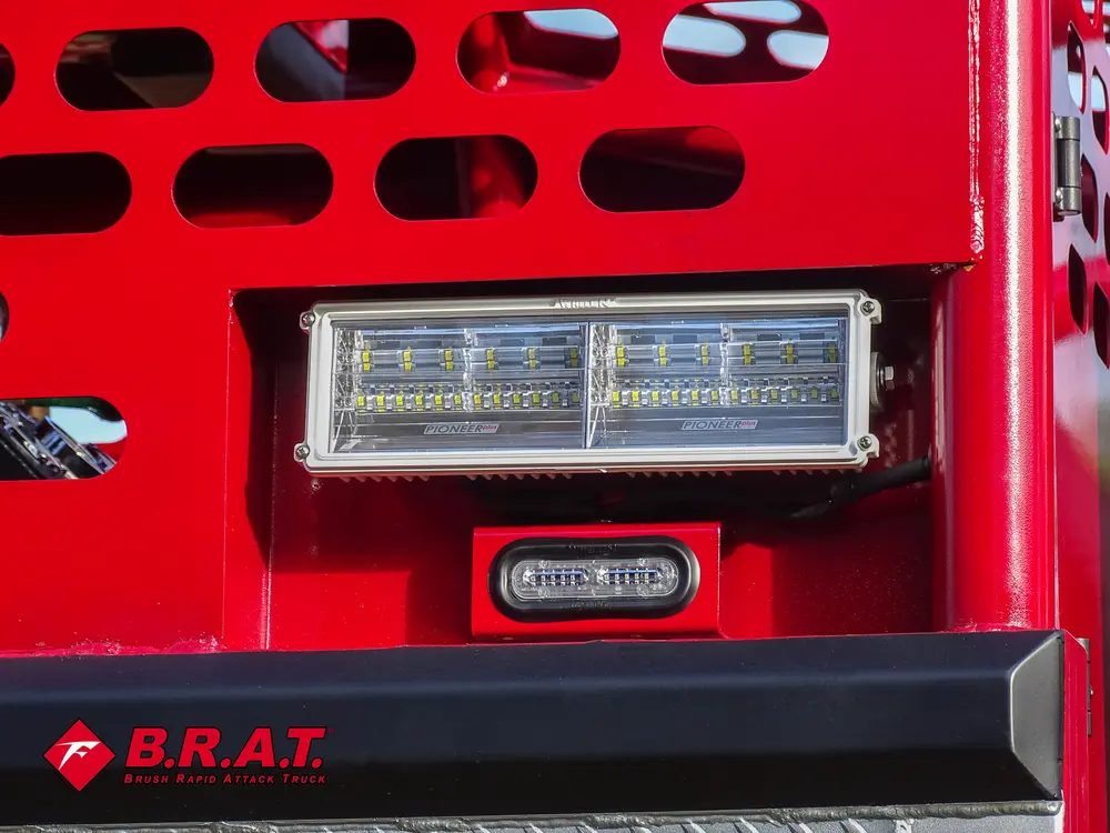 Exterior view of small fire truck showing cab, body compartments, and wheel/tire area.