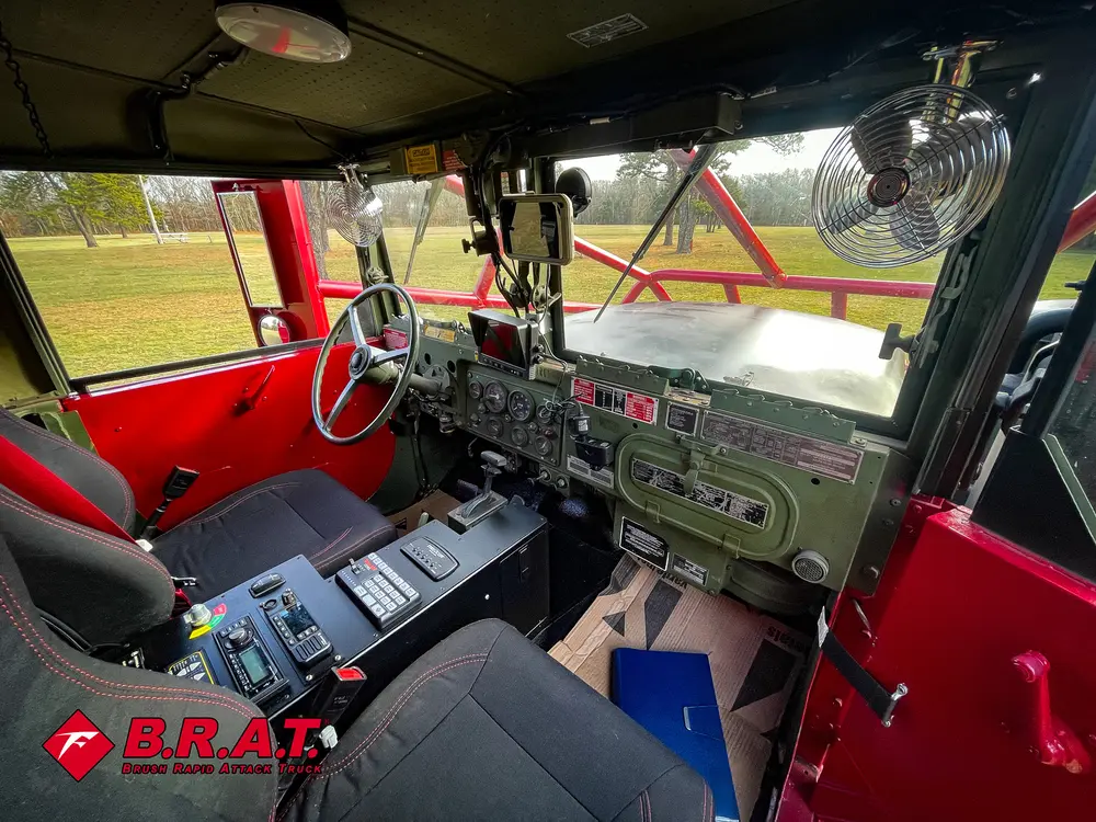 Exterior view of small fire truck showing cab, body compartments, and wheel/tire area.