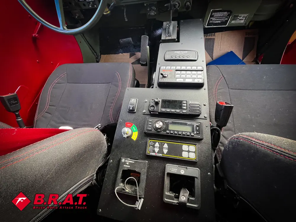 Exterior view of small fire truck showing cab, body compartments, and wheel/tire area.