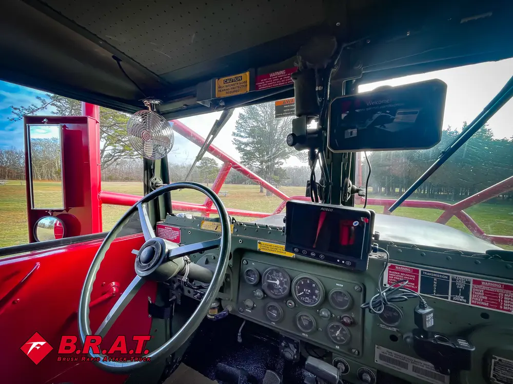 Exterior view of small fire truck showing cab, body compartments, and wheel/tire area.