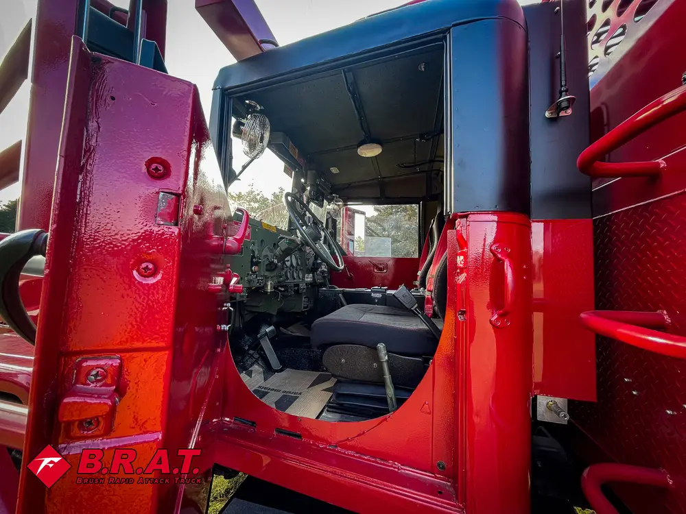Exterior view of small fire truck showing cab, body compartments, and wheel/tire area.