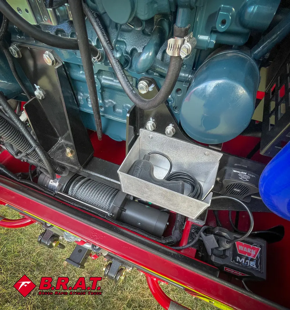 Exterior view of small fire truck showing cab, body compartments, and wheel/tire area.