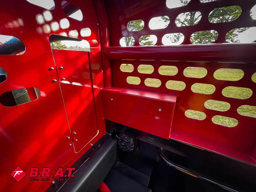 Exterior view of small fire truck showing cab, body compartments, and wheel/tire area.