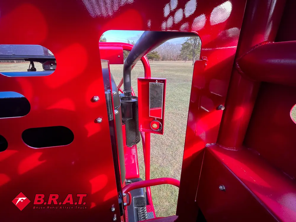 Exterior view of small fire truck showing cab, body compartments, and wheel/tire area.