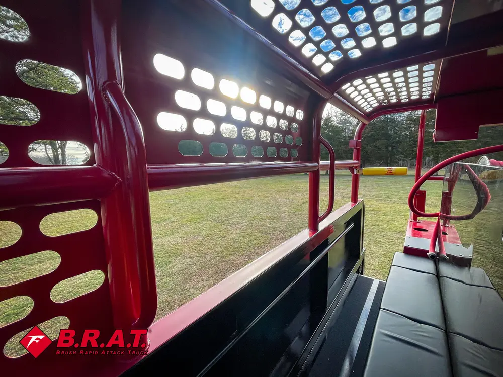 Exterior view of small fire truck showing cab, body compartments, and wheel/tire area.