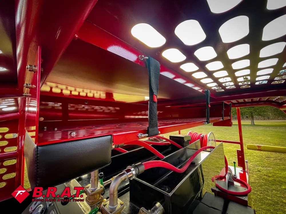 Exterior view of small fire truck showing cab, body compartments, and wheel/tire area.